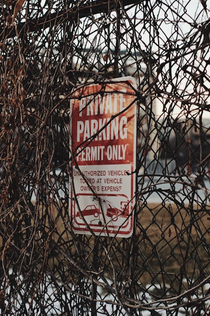 A black and white rectangular sign attached to a grey metal gate, displaying the words 'PRIVATE PROPERTY NO TRESPASSING' in bold capital letters, with the bottom section left blank. The gate is part o